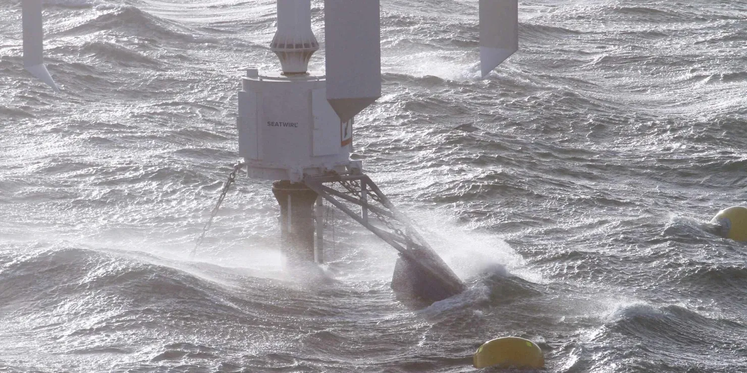 Close-up of the generator house at the waterline with foam and spray around it, in muted greys