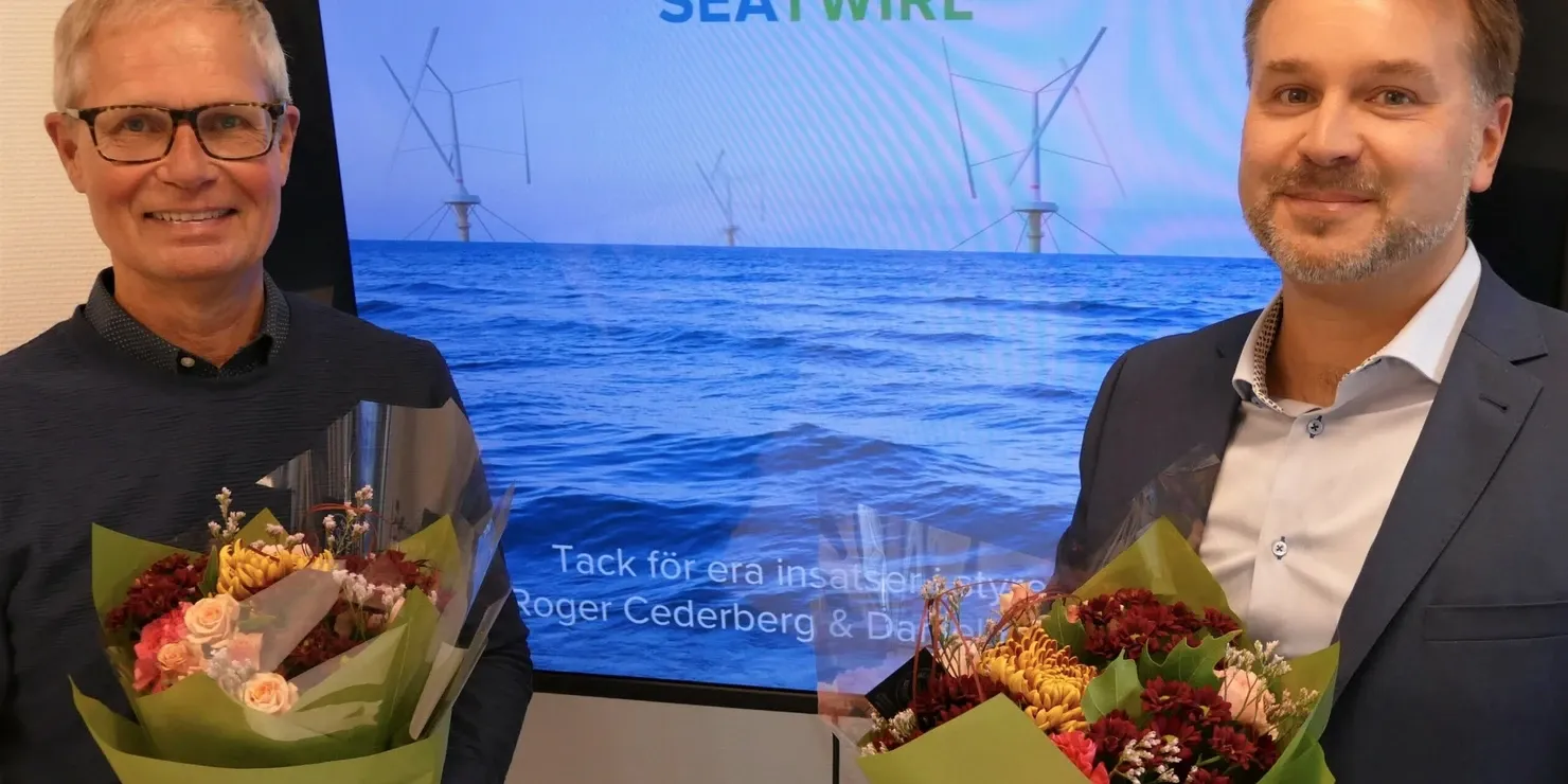 Two men each holding a bouquet of flowers in front of a screen with the text “Tack för era insatser Roger Cederberg & Daniel Ehrnberg”